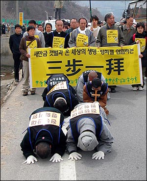 3보1배를 시작한 문규현 신부와 수경 스님. 등 에는 '전쟁반대 평화기원'이라고 적힌 종이를 달았다. 